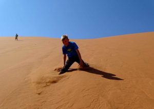 Ein Kind tollt in den Dünen am Sossusvlei in Namibia